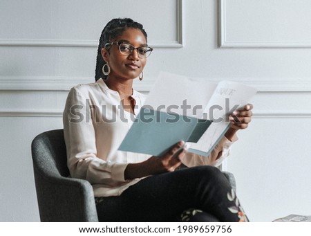 Happy black woman reading a unique magazine