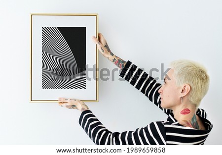 Woman hanging a photo frame on a white wall