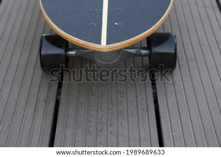 Tip of black color newly unpack surf skateboard with its round black color small wheel on tile floor with empty space under concept of recreational activity under corona virus pandemic era at home