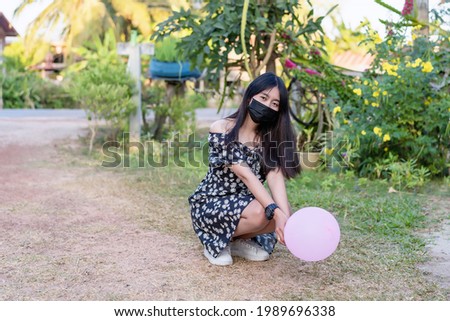 Portrait of young woman wearing black face medical mask to protect corona virus epidemic. Pretty happy student girl looking at camera outdoor. Coronavirus pandemic time of people. Health care concept