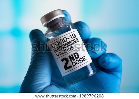 doctor with Coronavirus vaccine bottle with the name of the Second vaccine on the label. COVID-19 Vaccine Vial for vaccination tagged with 2nd dose Royalty-Free Stock Photo #1989796208