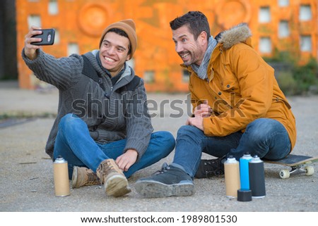 two friends taking a selfie next to a wall graffiti