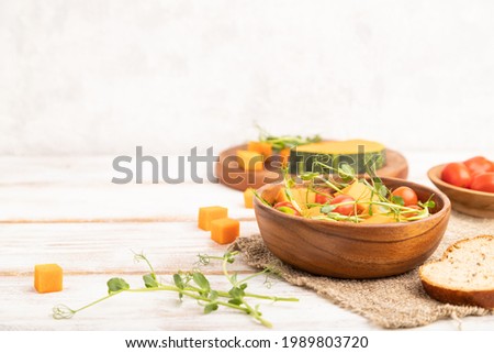 Vegetarian vegetable salad of tomatoes, pumpkin, microgreen pea sprouts on white wooden background and linen textile. Side view, copy space.