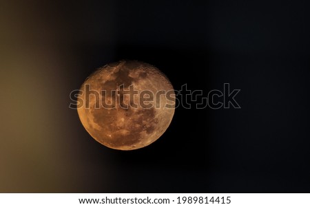 Beautiful full moon in the night sky with yellow light coming from the left side. Breathtaking image of the moon at midnight - half blurred with selective focus