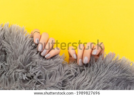 Womans hands holding furry fabric on yellow background
