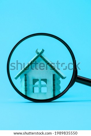 Miniature house and a magnifying glass on a bright colored background. View of the house through a magnifying glass. Real estate buying and selling concept. Search for housing. Side view.