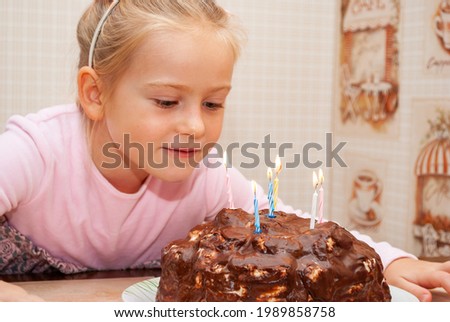 Baby girl makes a wish and blows out the candles on the cake. The child's birthday.