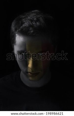 serios man face with painted flag colors of Belgium, black background