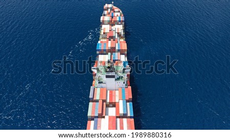 Aerial drone photo of huge container tanker ship carrying truck size colourful containers in deep blue Mediterranean sea