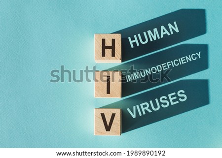Wooden cubes building word HIV - (abbreviation human immunodeficiency viruses) on light blue background