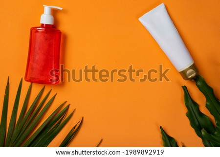 sunscreen and alcohol gel on orange summer beach background