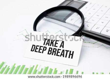 Business concept. Top view of calculator, magnifier, pen, table clock and notebook written Take a deep breath on wooden background.