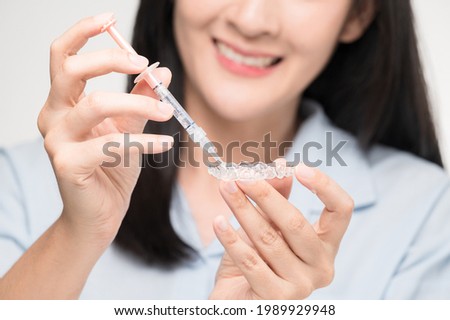 Tooth whitening gel being applied to a tooth mold in preparation for being placed in the mouth. Royalty-Free Stock Photo #1989929948