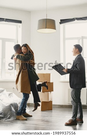 Real Estate Agent Shows Bright New Apartment to a Young Couple Royalty-Free Stock Photo #1989937556