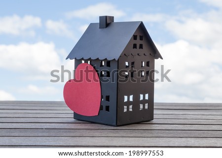 Black house with a heart and a blue sky in the background. Suitable for concepts such as house sales and broker.