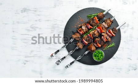 Traditional Kebab. Juicy pork skewers with vegetables on a black stone plate. Barbecue. Top view. Free space for text. Royalty-Free Stock Photo #1989994805
