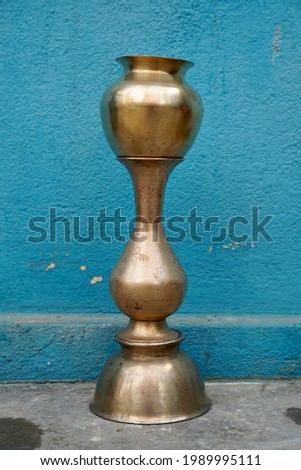 Brass utensils of drinking vessel, Flower pot and a jar kept isolated against the blue wall background. Vintage old vessels.