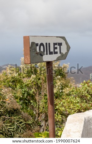 Restroom sign. Post with an arrow and the word Toilet indicating the direction to the bathroom.