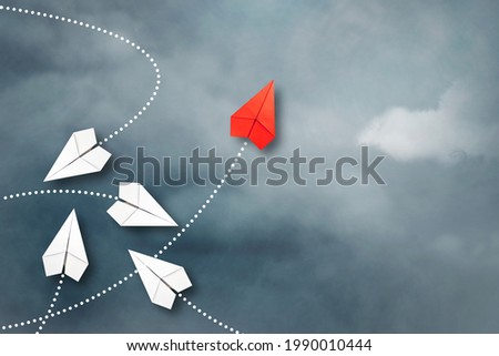 Red paper plane flying in a different direction than the white ones. Cloudy sky. Copy space. The concept of innovative solutions, creativity. Business. Lifestyle. Background.