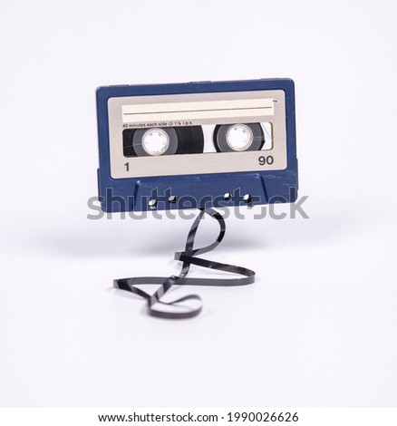 A flying cassette with the magnetic tape spilling out onto the floor Royalty-Free Stock Photo #1990026626