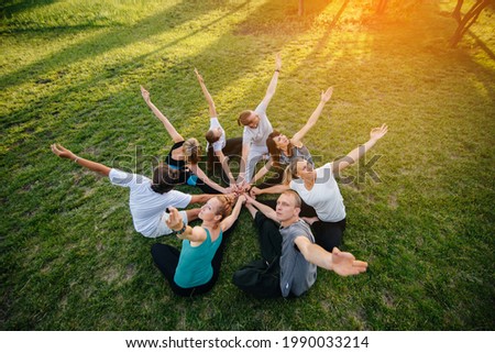 A group of people do yoga in a circle in the open air during sunset. Healthy lifestyle, meditation and Wellness Royalty-Free Stock Photo #1990033214