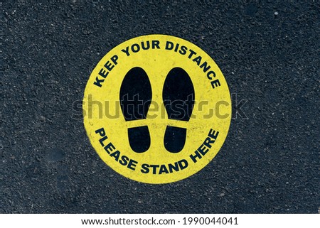 Keep your distance sign on asphalt sidewalk
