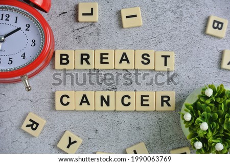Block written with BREAST CANCER isolated on ceramic background inscription with watch, and flower.