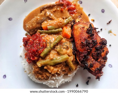 Malaysian dish comprise of white rice with vegetables curry and spice fried chicken also known as "nasi kak wok" Royalty-Free Stock Photo #1990066790