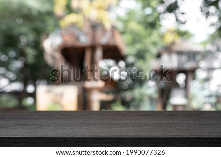 Empty wooden table with blurry background of tree houses or resort.