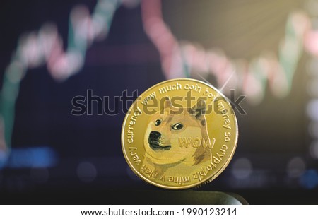 Dogecoin, a cryptocurrency meme in a close-up on the background of the graph, in the dark Royalty-Free Stock Photo #1990123214