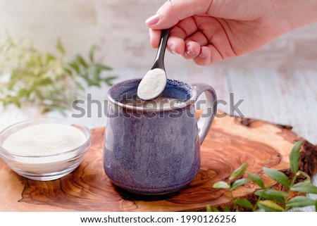 Woman adding collagen powder to her morning coffee. Beauty collagen supplement, additional collagen intake Royalty-Free Stock Photo #1990126256