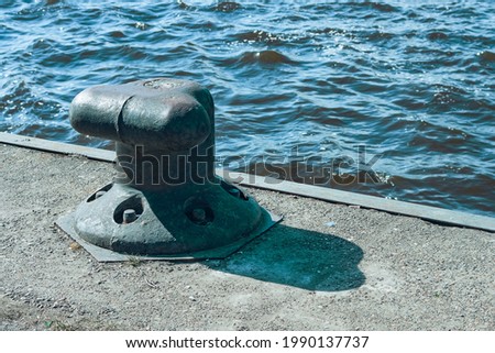 A lonely old metal mooring bollard on the pier.
