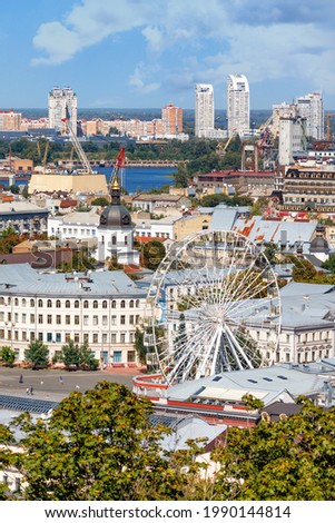 A view of the old Podil, summer Kyiv, the Ferris wheel, dense residential buildings and a new neighborhood on the horizon. Vertical image.