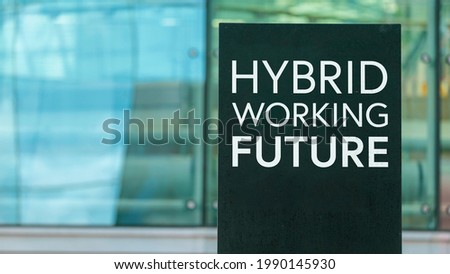 Hybrid Working Future on a sign outside a modern glass office building	
