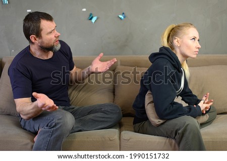 Photo of a man at home with a woman on a sofa sitting swears right in front of the camera