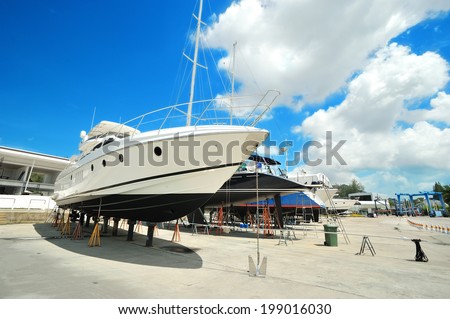 Luxury motor yacht beached at a dock for painting and repair Royalty-Free Stock Photo #199016030