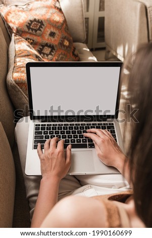 Woman working on laptop lying on the couch. Eastern traditional home interior design concept. Oriental style living room sofa, pillows. Blank copy space screen