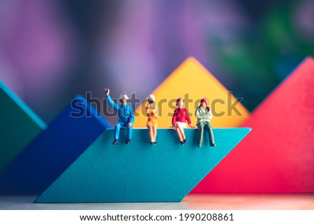 Miniature people, man and woman sitting on colorful wooden block using as business and social concept Royalty-Free Stock Photo #1990208861