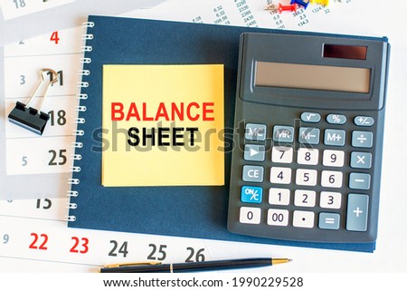 yellow piece of paper with the text balance sheet and the calculator are lying on the notepad. the notebook and pen are placedes on the documents pages. business and financial concept. selective focus