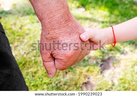 old man holding child's hands. selective focus people