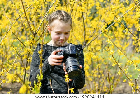 A young girl photographs nature in the park with a SLR camera.