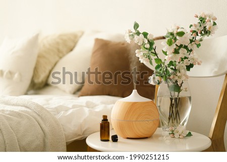 Aromatherapy Concept. Aroma oil diffuser on chair against in the bedroom. Air freshener. Ultrasonic aroma diffuser for home Royalty-Free Stock Photo #1990251215