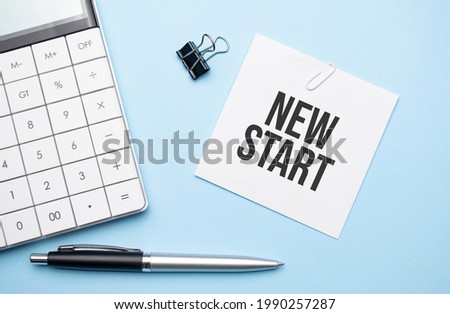 On a blue background, glasses, calculator, coffee, magnifier, pen and notebook with the text new start