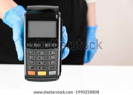 Close up woman in rubber gloves holding a pos terminal. Contactless payment during pandemic using nfc technology Royalty-Free Stock Photo #1990258808