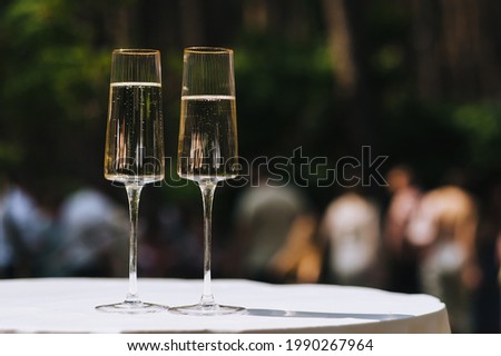 Two glass glasses of champagne are on the table with a white tablecloth.