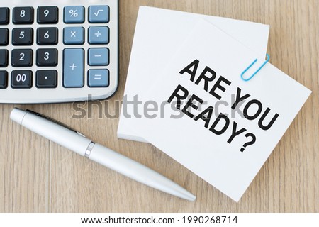 Are you ready inscription on a white card, which is on the table next to a pen and a calculator