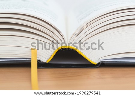 Open book with a bookmark on a wooden table close-up.