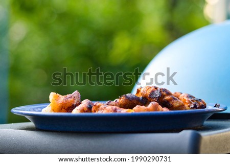 A few pieces of grilled meat on a blue plate on a grill