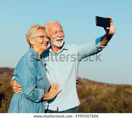 Happy active senior couple taking selfie outdoors