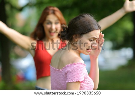 Stressed woman avoiding to meet her friend walking in a park Royalty-Free Stock Photo #1990335650